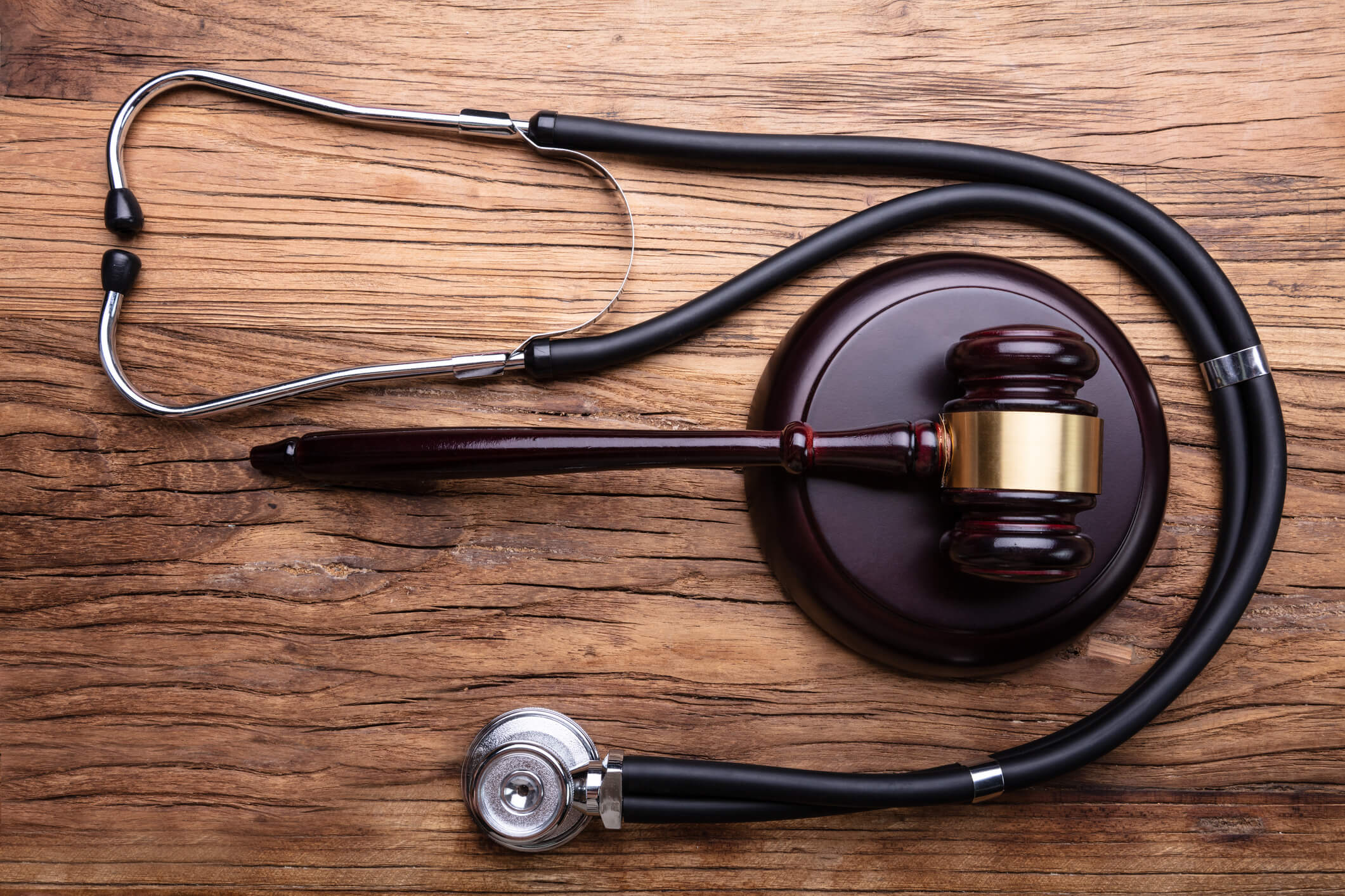 High Angle View Of Gavel With Stethoscope Arranged On Wooden Table