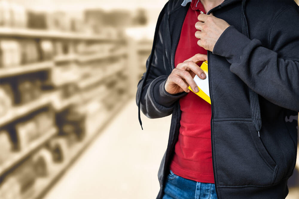 a man shoplifting a product by hiding in his coat
