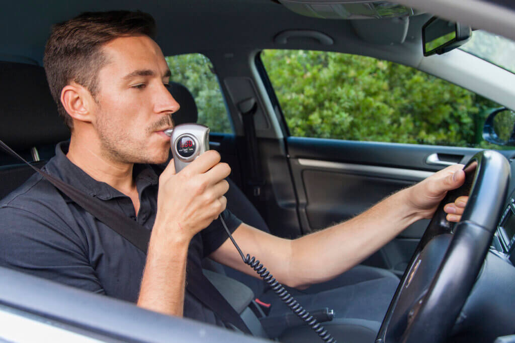 a man blowing into an ignition interlock device to start his car