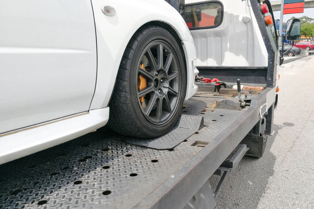 seized car towed onto flatbed tow truck with hook and chain